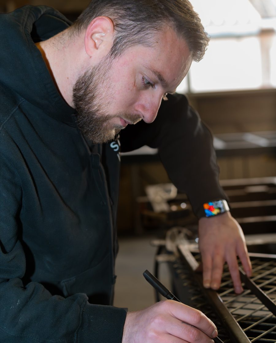 Ferronnier ajustant un panneau de maille d’acier à l’établi de l’atelier